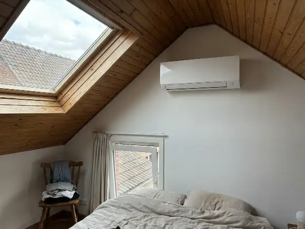 Binnenunit van een airco boven een raam in een zolderkamer